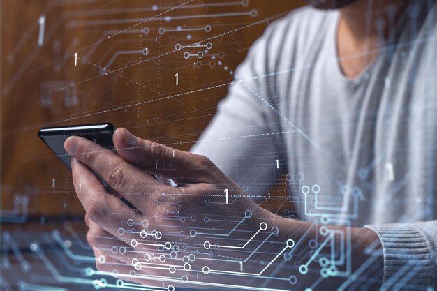 Programador sosteniendo en las manos un teléfono inteligente y probando una aplicación innovadora para proporcionar un servicio completamente nuevo Primer plano Gráficos tecnológicos de holograma Concepto del equipo de desarrollo