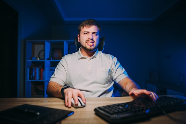 Programador trabalha à noite em um computador em uma sala com luz azul