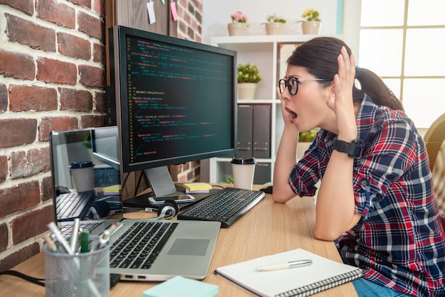 programadora asiática que se siente loca y abrumada por trabajar en la oficina.