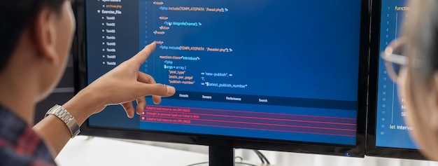Programadora explica mientras señala el código mostrado en la computadora Programadora profesional presenta análisis de datos y escritura de JavaScript en la oficina moderna de la compañía Closeup Burgeoning