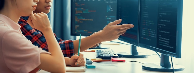 Programadora explica mientras señala el código mostrado en la computadora