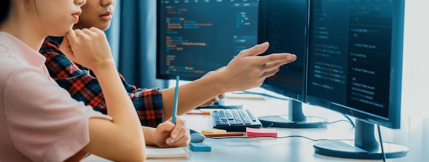 Programadora explica mientras señala el código mostrado en la computadora