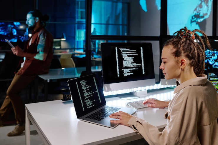 Foto programadora seria con rastas decodificando datos en la pantalla del portátil