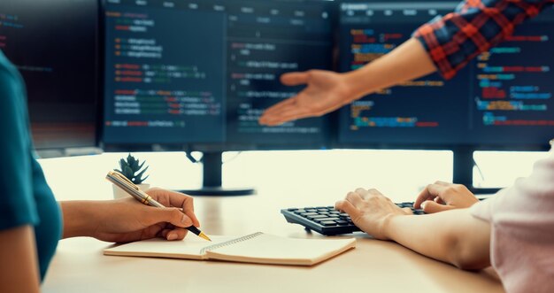 Programadora tomando una nota mientras el desarrollador web presenta el programa en auge