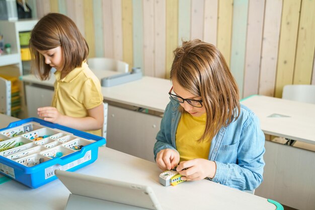 Foto programmierarbeit lernen robotik in der grundschule kinder schüler montieren starten die kodierung von robotern konstruktionsteile nach anweisungen in tablet stem-ausbildung wissenschaft ingenieurwesen klasse