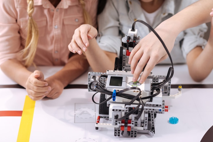 Foto progreso tecnológico. niños hábiles e inventivos que se sientan en la escuela y disfrutan de la clase de tecnología mientras construyen un robot