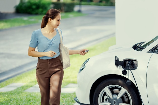 Progressive Frau lädt ihr EV-Auto an der Ladestation zu Hause auf