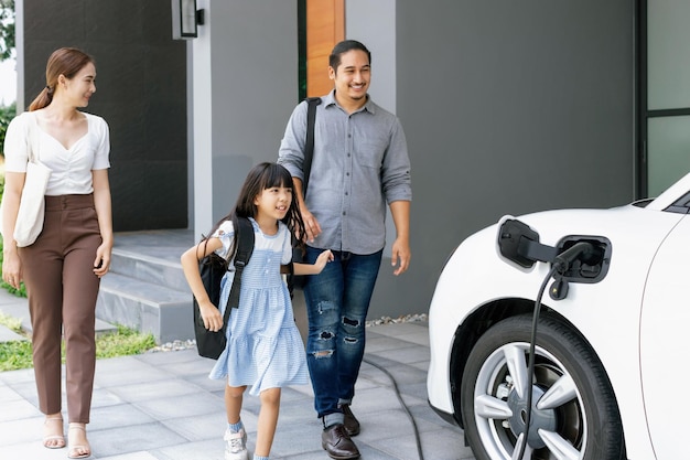 Progressive junge Eltern und Tochter, die in einem Haus mit einem Elektroauto leben