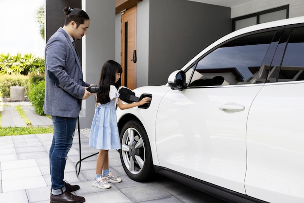 Progressiver Vater und Tochter, die EV-Auto von der Ladestation zu Hause aufladen