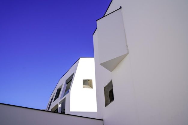 Projete o edifício moderno branco da fachada no distrito novo real em um céu azul