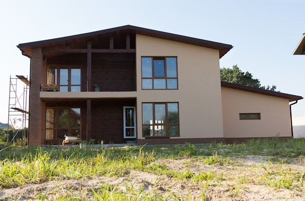 Projeto de construção imobiliária marrom arquitetônico inacabado na paisagem gramada.