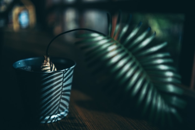 Projeto de decoração de plantas em estilo minimalista de fundo, xícara de bebida na mesa de madeira natural, interior moderno de parede verde em uma sala de cafés caseiros, bebida quente e luz do sol pela manhã