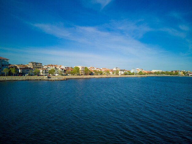 Promenade mit Passanten in der Nähe des Schwarzen Meeres vor dem Hintergrund der Stadt Pomorie in Bulgarien unter einem bewölkten Himmel