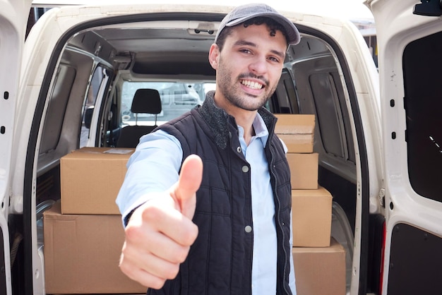 Le prometo un servicio de calidad Retrato de un joven repartidor que muestra el pulgar hacia arriba mientras carga cajas de una furgoneta