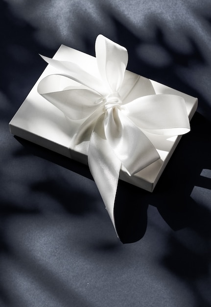 Promoção de venda de loja de comemoração de aniversário e conceito surpresa de luxo caixa de presente branca de luxo com fita de seda e laço em fundo preto casamento luxuoso ou presente de aniversário