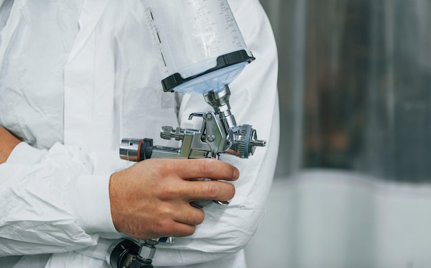 Pronto para a pintura O homem de uniforme está trabalhando no auto serviço