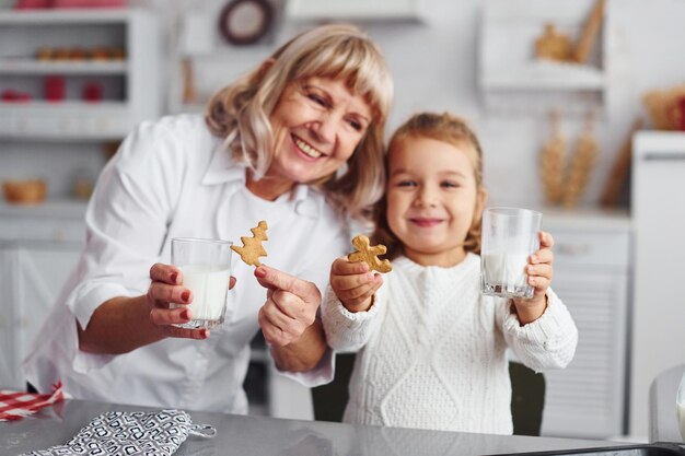 Pronto para comer avó sênior com sua neta cozinha doces para o natal na cozinha