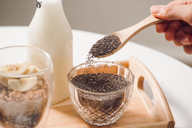 Foto pronto para comer saudável e nutritivo café da manhã - granola com amêndoas, sementes de chia, banana e kiwi e frutas vermelhas e uma jarra com leite por perto