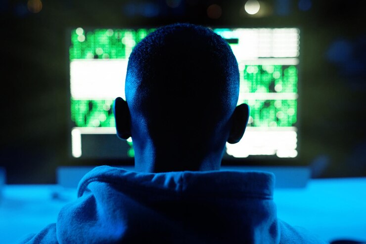 Foto pronto toda su información será mía vista trasera de un hacker descifrando un código de computadora en la oscuridad