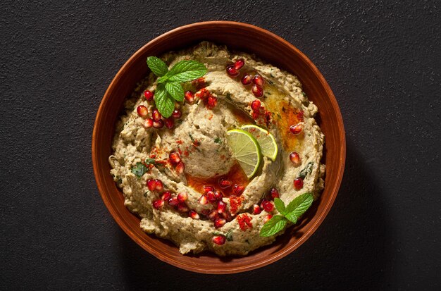 Propagación casera de berenjena al horno baba ganoush en un recipiente con semillas de granada