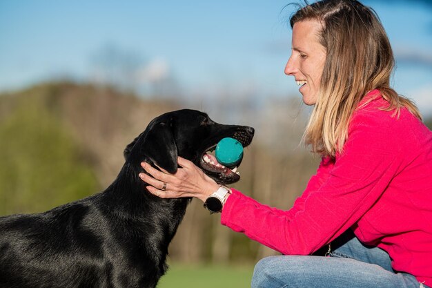 Propietario alabando a su labrador retriever llevándole un maniquí