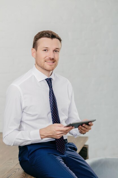 Foto el propietario de la empresa financiera con atuendo elegante lee los chats de notificación en el panel táctil y sonríe con confianza concepto de personas y tecnología