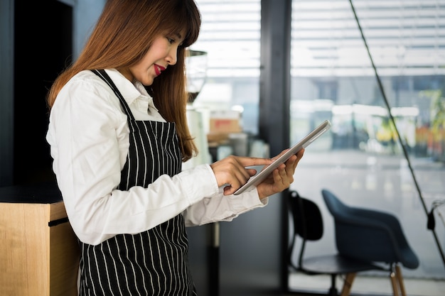 propietario de una empresa que sostiene la tableta de pie frente a la cafetería con una sonrisa