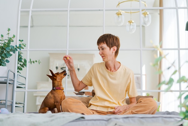 Propietario jugando con un perro alegre en casa mujer madura feliz disfrutando del ejercicio