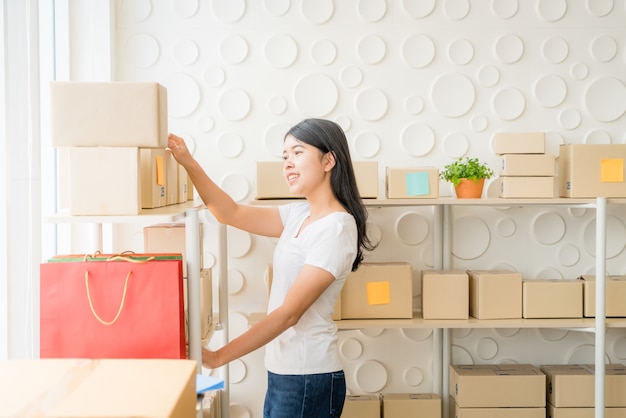 Propietario de negocio de mujeres asiáticas trabajando en casa con caja de embalaje en el lugar de trabajo