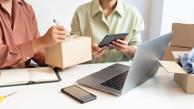 Propietario de pareja de negocios asiáticos que trabaja en casa con caja de embalaje de su tienda en línea se prepara para entregar