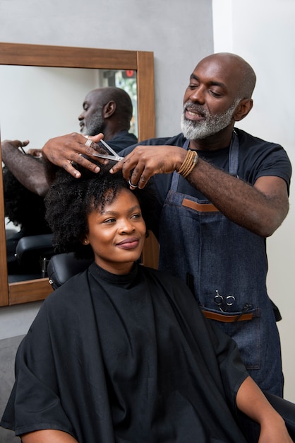 Foto propietario de peluquería latina cuidando a un cliente