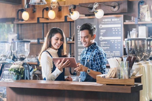 Propietario de una pequeña empresa asiática joven hablando con colegas y usando tableta de tecnología