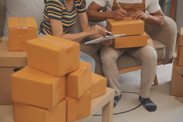 Foto propietario de una pequeña empresa emergente que trabaja con una computadora en el lugar de trabajo vendedor independiente de dos mujeres verifica el pedido del producto embalaje de productos para entregarlos al cliente venta en línea comercio electrónico compras en línea