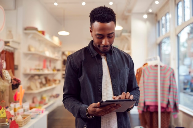 El propietario de una pequeña empresa masculina comprueba las existencias en la tienda mediante una tableta digital