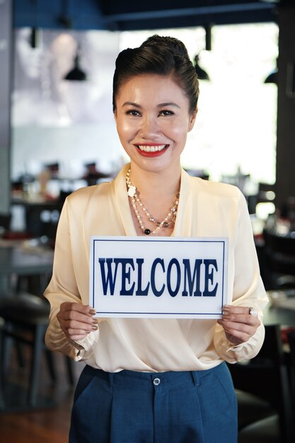 Foto propietario del restaurante con cartel de bienvenida