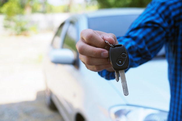 El propietario del vehículo está de pie las llaves del coche al comprador.