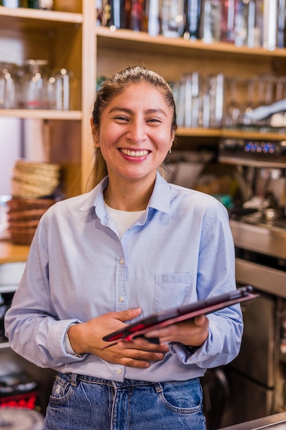 Foto proprietária de uma pequena empresa de negócios usando a tecnologia de tablet, jovem empreendedora peruana de bistrô latinx