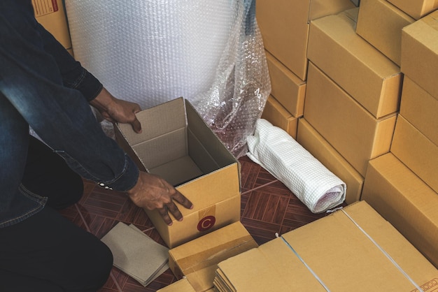 Proprietário da empresa masculina trabalhando embalando o pedido para envio à caixa de embalagem do cliente para entrega