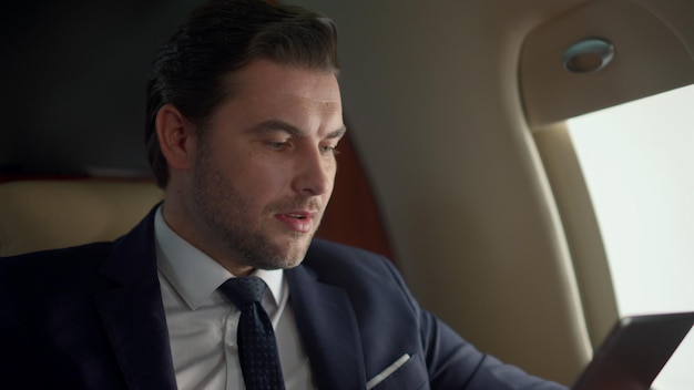 Proprietário da empresa usando tablet na janela do avião Homem estressado contempla