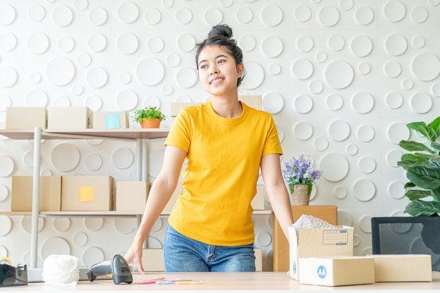 Proprietário de empresa mulher asiática trabalhando em casa com caixa de embalagem no local de trabalho