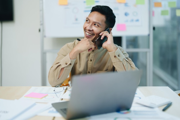 Proprietário de empresas ou comerciantes masculinos asiáticos estão usando telefones e computadores comerciais para fazer trabalho de escritório