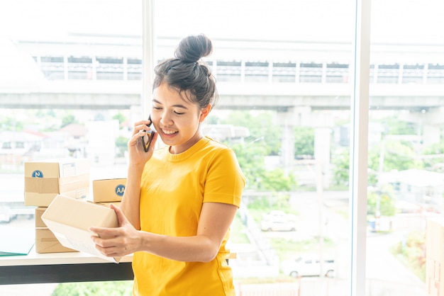 Proprietário de negócios de mulheres asiáticas trabalhando em casa com a caixa de embalagem no local de trabalho