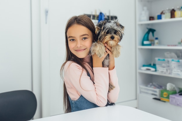 Proprietário de uma menina pequena e bonita com seu lindo Yorkshire Terrier na clínica veterinária.