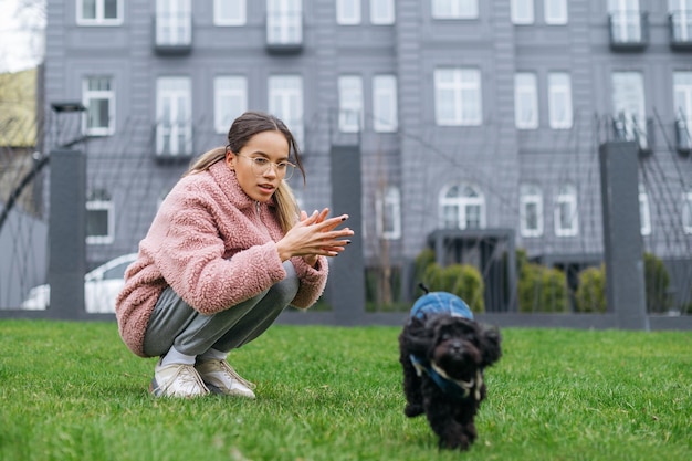 Proprietário e o cachorro criam poodle toy andando na rua mulher andando com um cachorrinho no quintal