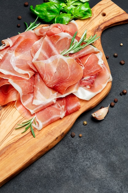 Prosciutto crudo italiano o jamón español. Jamón crudo sobre tabla para cortar madera