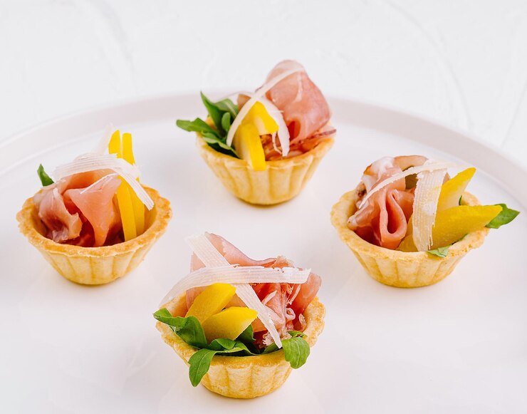 Prosciutto gourmet y canapés de melón en un plato blanco