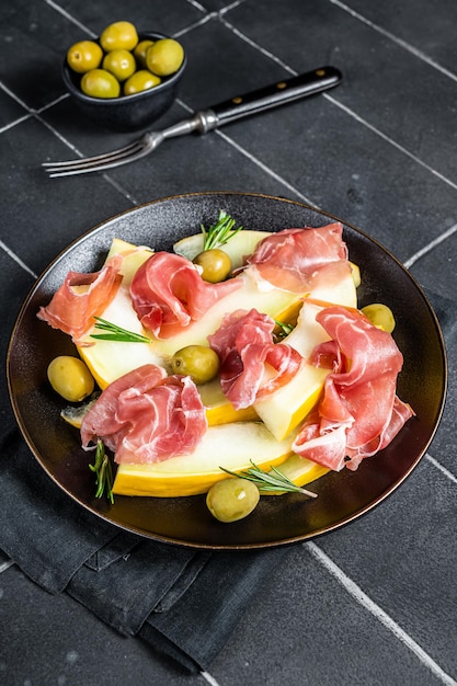 Prosciutto-Schinken- und Melonsalat auf einem Teller Schwarzer Hintergrund Top-View