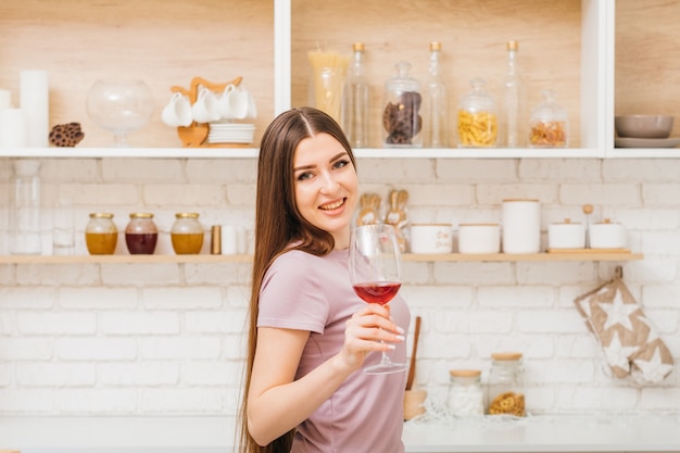 Prost. Partyspaß zu Hause. Zeit zum Entspannen. Schöne junge Frau mit Weinglas. Küchenraum zu Hause.