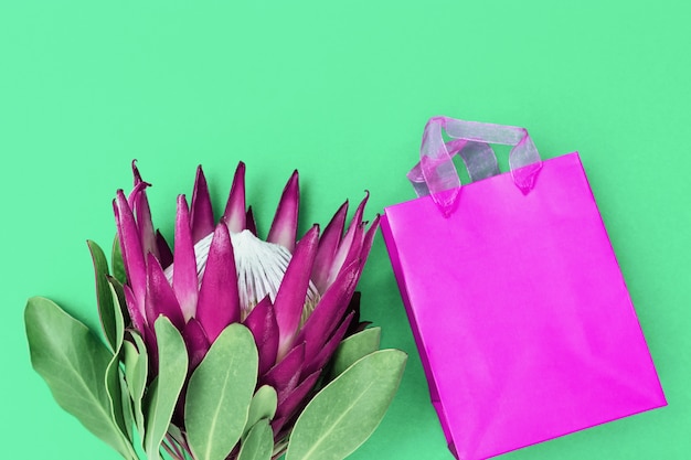 Protea flor grande exótica con pétalos violetas y presente en caja de papel decorada