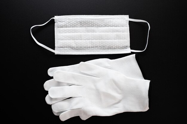 Protección contra coronavirus Mascarilla médica antibacteriana blanca y guantes protectores sobre fondo negro